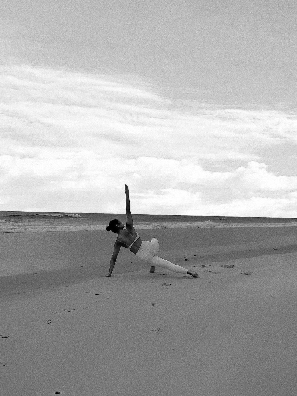 Christine practising yoga on the beach, in black and white