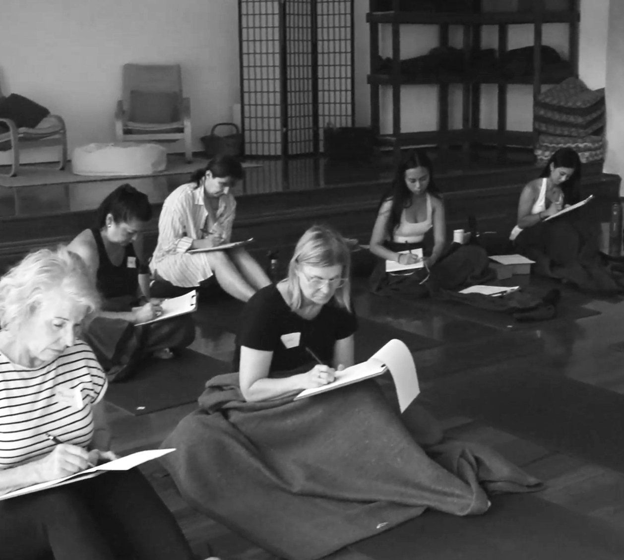 Participants journaling together on the studio floor, in black and white