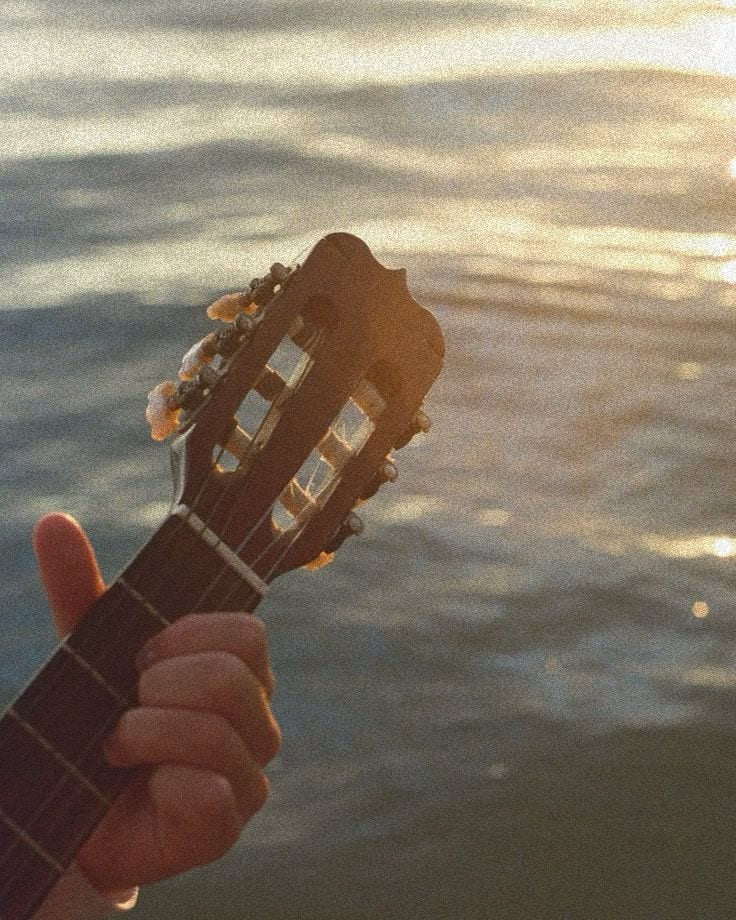 Playing guitar by the water at sunset