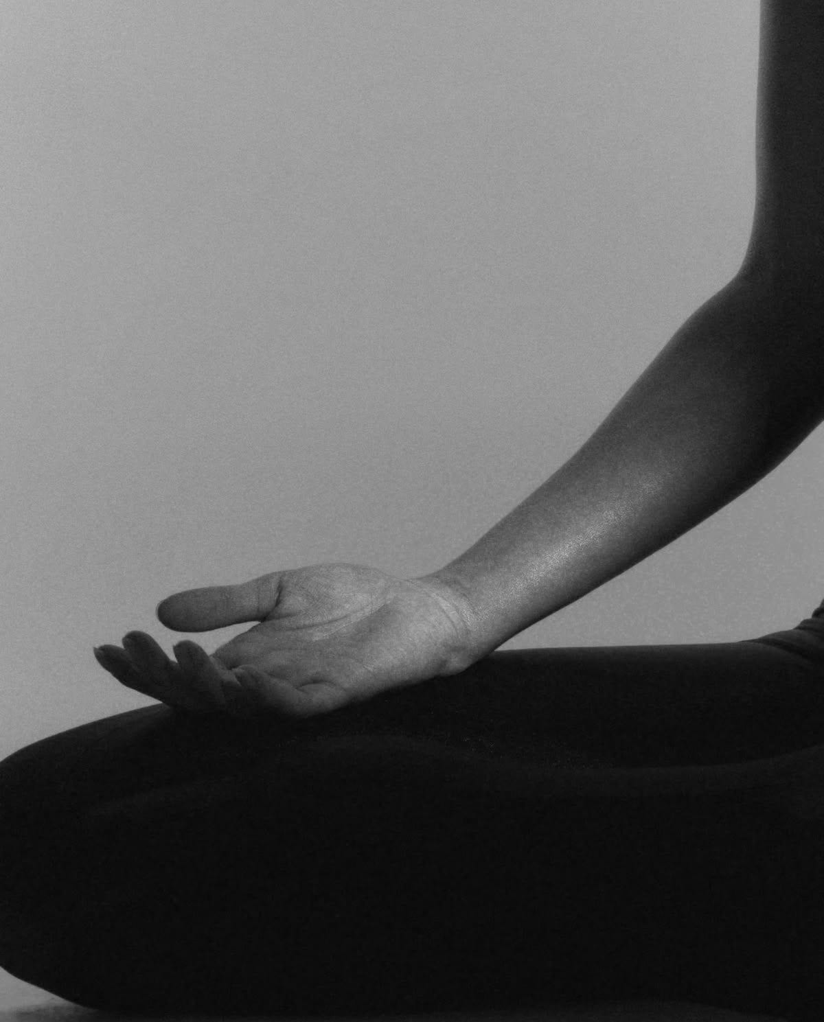 An open hand resting in a meditation mudra, in black and white