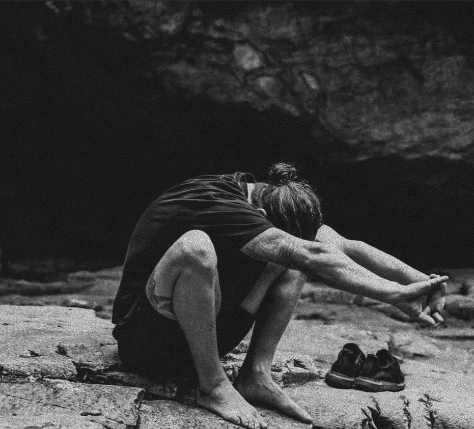 A man stretching on coastal rocks, in black and white