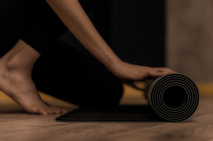 Hands unrolling a yoga mat in warm light